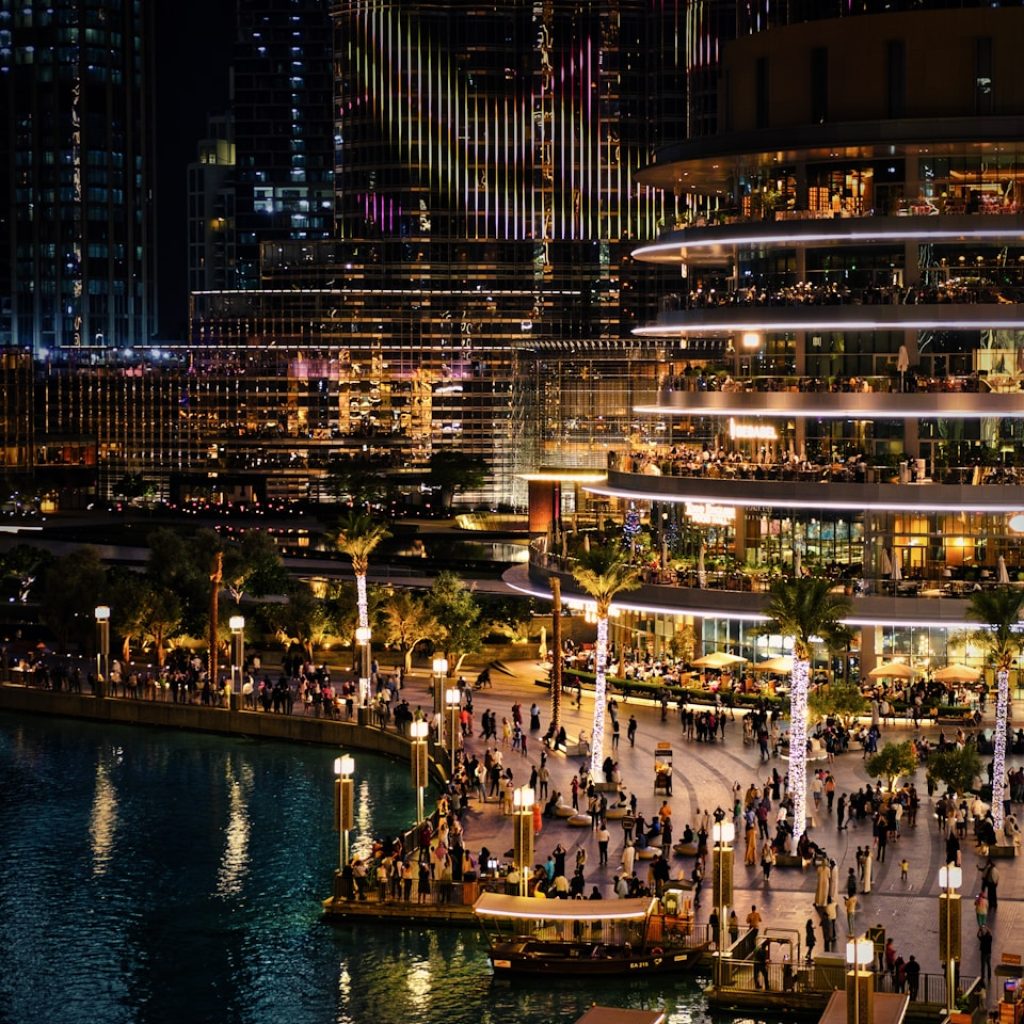 people walking on sidewalk near body of water during night time